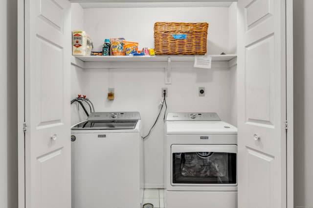 clothes washing area with washing machine and dryer and tile patterned floors