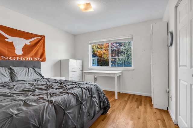 bedroom featuring light hardwood / wood-style floors, a textured ceiling, and a closet