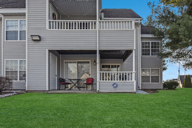 rear view of property featuring a lawn and a balcony