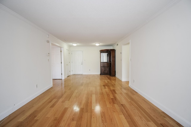 empty room with crown molding and light hardwood / wood-style flooring