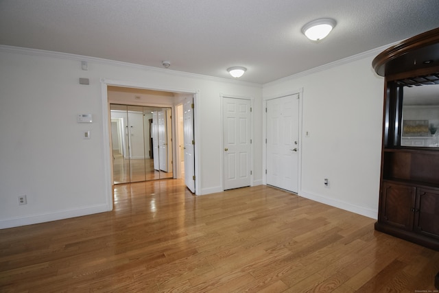 unfurnished room featuring a textured ceiling, light hardwood / wood-style flooring, and ornamental molding