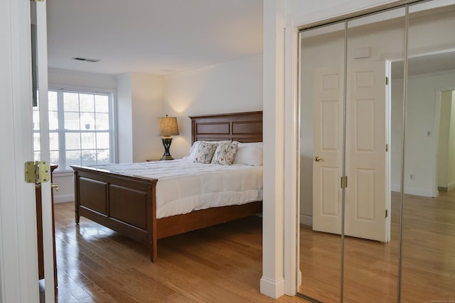 bedroom featuring hardwood / wood-style flooring, crown molding, and a closet