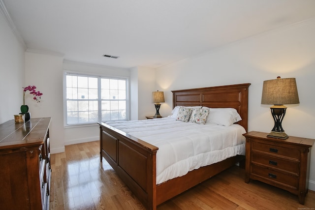 bedroom featuring light wood-type flooring and crown molding