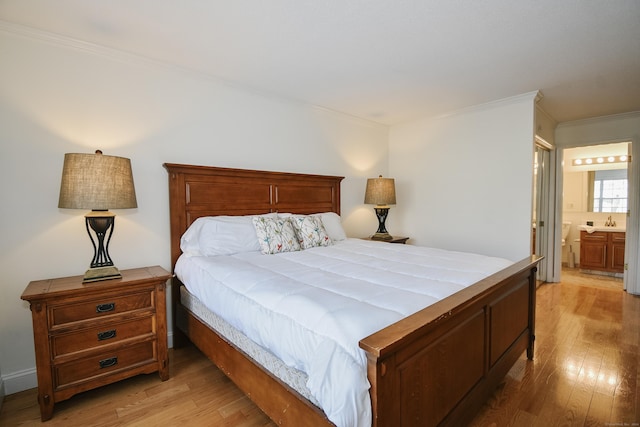 bedroom featuring ensuite bathroom, ornamental molding, and light wood-type flooring