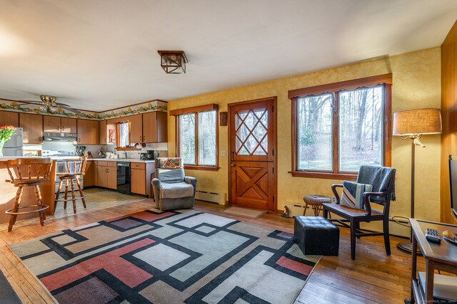 living room with ceiling fan, light hardwood / wood-style floors, and a baseboard radiator