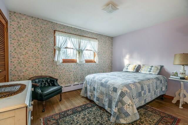 bedroom with hardwood / wood-style flooring and a baseboard heating unit