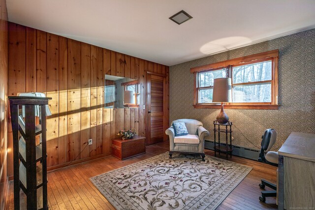 home office featuring hardwood / wood-style floors, a baseboard radiator, and wooden walls