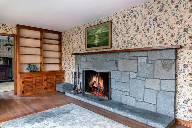 unfurnished living room with a stone fireplace and dark hardwood / wood-style flooring