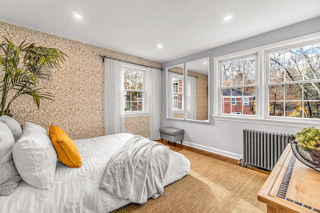 bedroom featuring radiator, hardwood / wood-style floors, and multiple windows