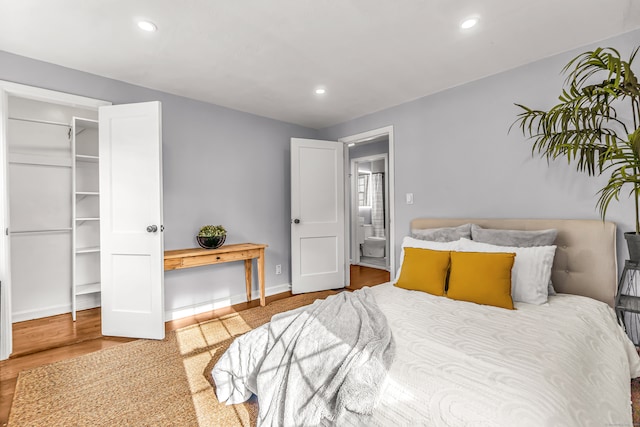 bedroom featuring a walk in closet, a closet, and hardwood / wood-style flooring