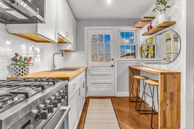 kitchen with light hardwood / wood-style flooring, white cabinetry, sink, decorative backsplash, and appliances with stainless steel finishes