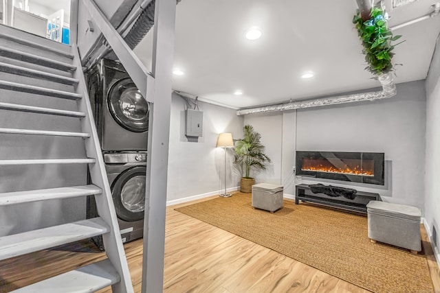 interior space with electric panel, stacked washing maching and dryer, and wood-type flooring