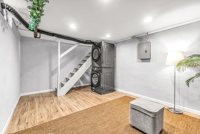 basement featuring hardwood / wood-style floors, electric panel, and stacked washing maching and dryer