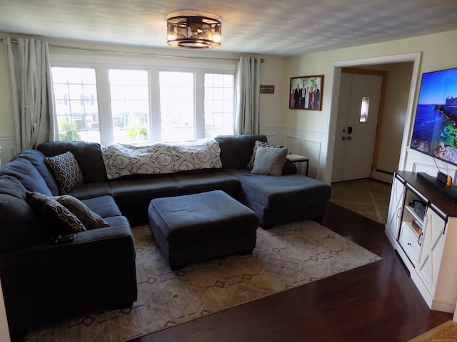 living room featuring baseboard heating, a wealth of natural light, and dark hardwood / wood-style flooring