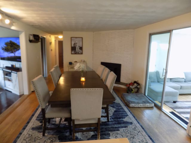 dining room with dark wood-type flooring and a fireplace