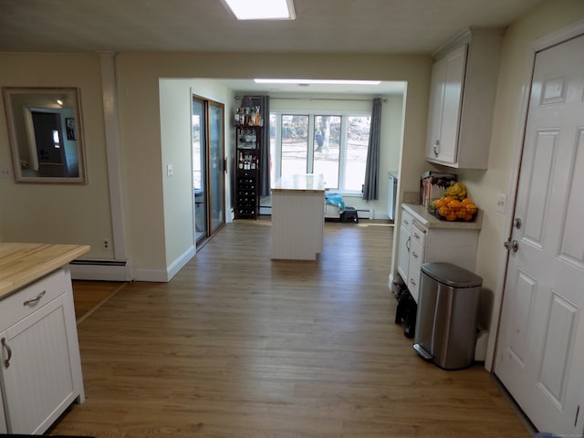 kitchen with white cabinetry, light hardwood / wood-style floors, and baseboard heating