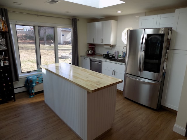 kitchen with white cabinets, light wood-type flooring, stainless steel appliances, and wood counters