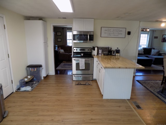 kitchen with stainless steel appliances, light hardwood / wood-style floors, white cabinetry, and plenty of natural light