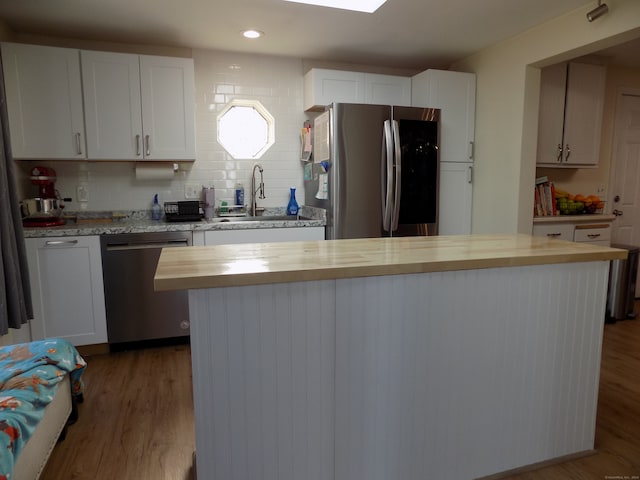 kitchen with butcher block counters, white cabinetry, sink, appliances with stainless steel finishes, and wood-type flooring