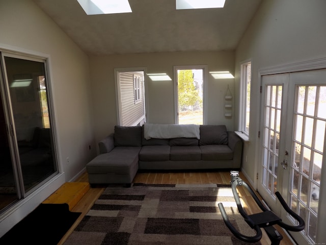 living room featuring vaulted ceiling with skylight and wood-type flooring