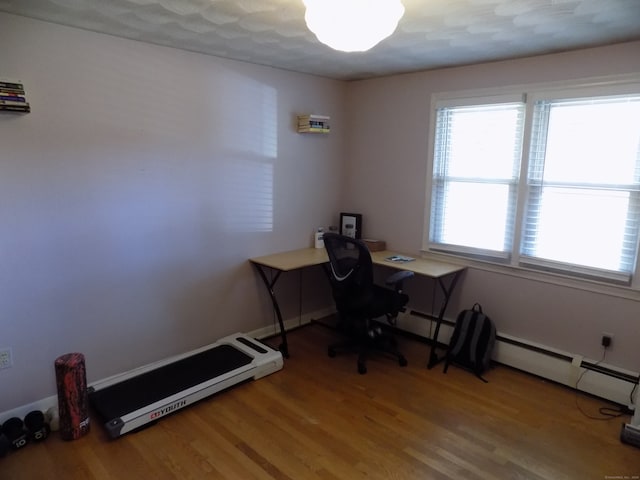 unfurnished office with a baseboard radiator and hardwood / wood-style flooring