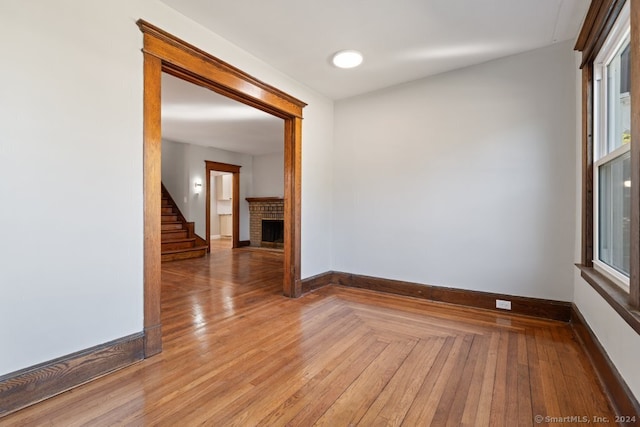 unfurnished room with a brick fireplace and light wood-type flooring