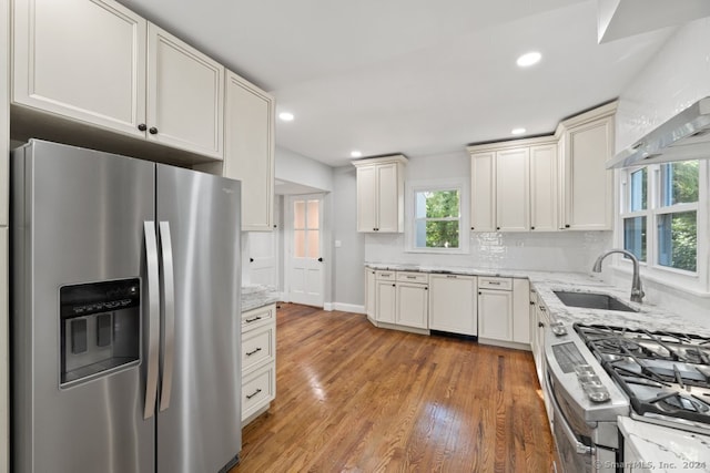 kitchen featuring light stone countertops, tasteful backsplash, stainless steel appliances, sink, and hardwood / wood-style flooring