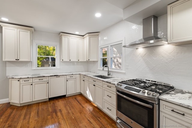 kitchen with sink, dark wood-type flooring, wall chimney range hood, light stone counters, and stainless steel range with gas cooktop