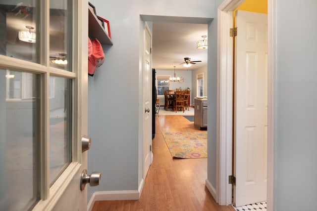 hallway featuring a notable chandelier and light hardwood / wood-style flooring