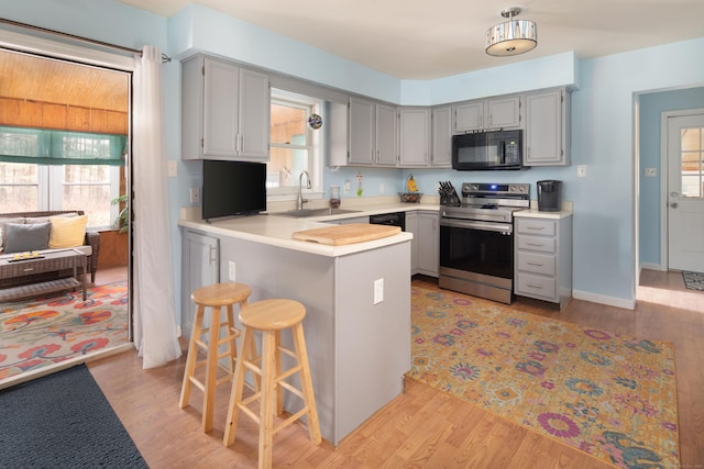 kitchen featuring stainless steel electric range, plenty of natural light, kitchen peninsula, and light hardwood / wood-style flooring