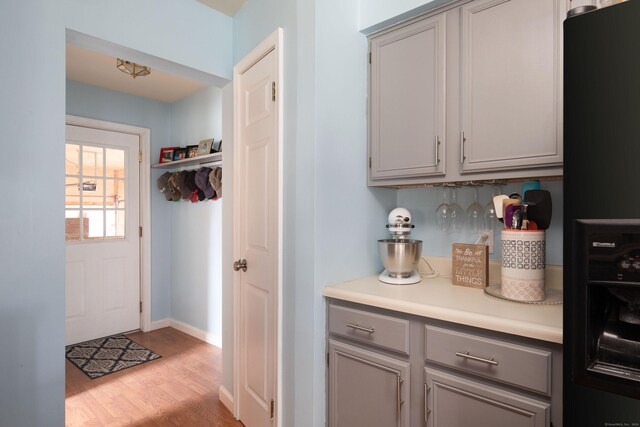 interior space featuring black fridge, backsplash, gray cabinets, and light hardwood / wood-style flooring