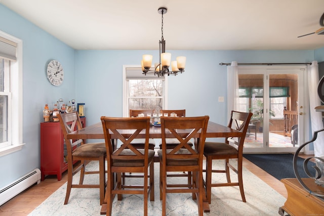 dining room featuring light hardwood / wood-style floors, a wealth of natural light, a baseboard heating unit, and a notable chandelier