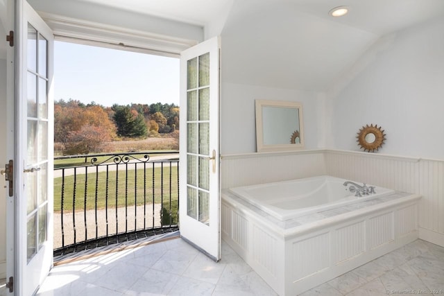 10 N Beaver Dam Rd, Salisbury, CT 06068 - bathroom featuring marble look tile flooring, a bath, wainscoting, vaulted ceiling, and french doors