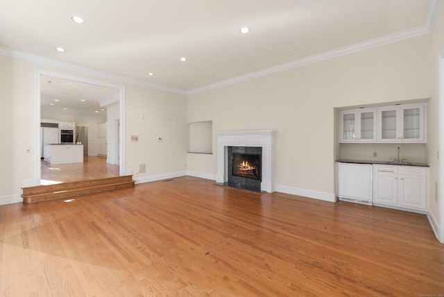 unfurnished living room featuring ornamental molding, a high end fireplace, and light hardwood / wood-style flooring