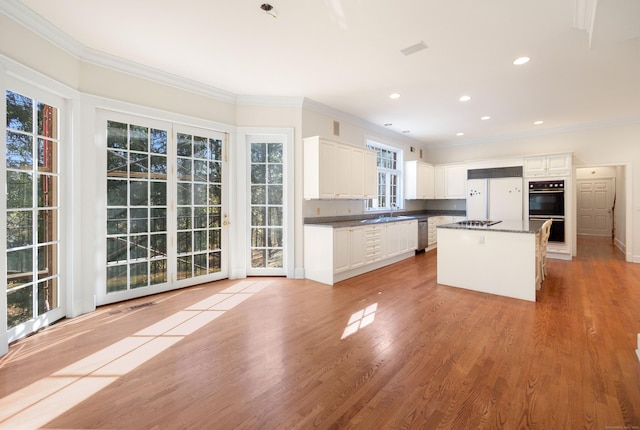 kitchen featuring white cabinets, light wood-type flooring, stainless steel appliances, and a kitchen island