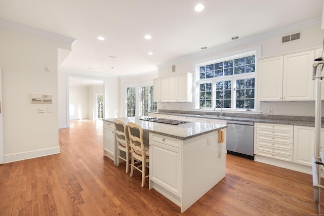 kitchen with appliances with stainless steel finishes, white cabinetry, a kitchen island, and sink