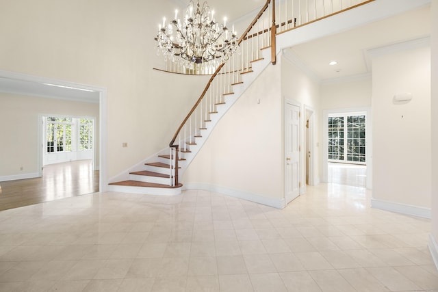 staircase featuring a notable chandelier, a towering ceiling, and crown molding