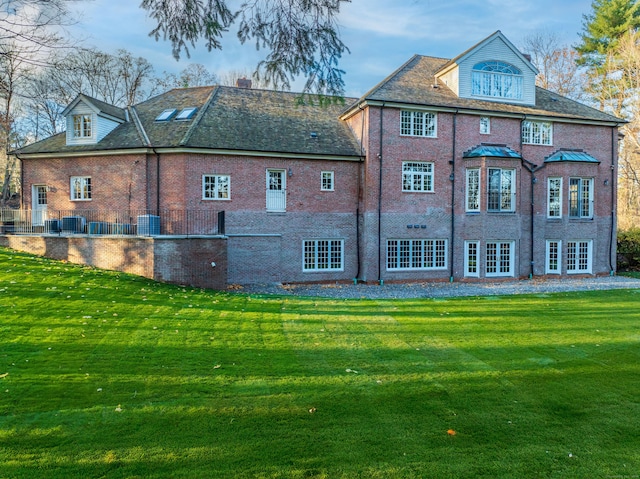 rear view of property with a lawn and central AC unit