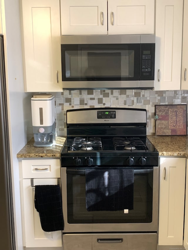 kitchen featuring white cabinets, decorative backsplash, stone countertops, and stainless steel appliances