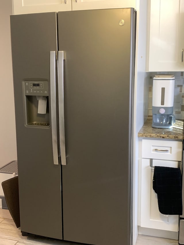 interior details with white cabinets, stone countertops, decorative backsplash, and stainless steel fridge with ice dispenser