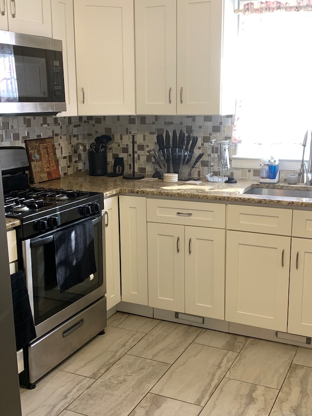 kitchen with backsplash, white cabinets, sink, and appliances with stainless steel finishes