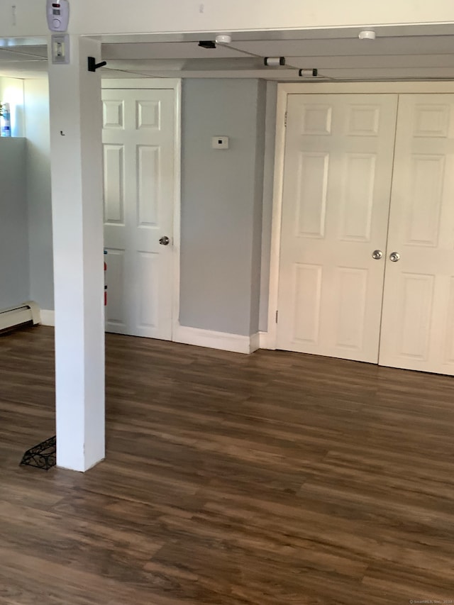 unfurnished bedroom featuring baseboard heating and dark hardwood / wood-style flooring