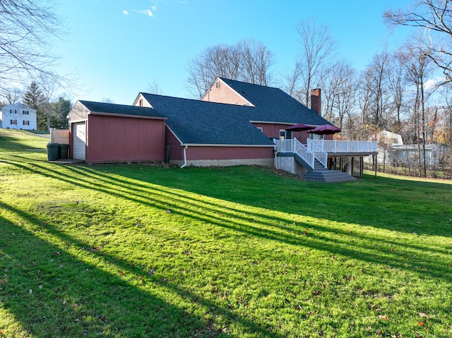 rear view of house featuring an outdoor structure, a garage, a yard, and a wooden deck