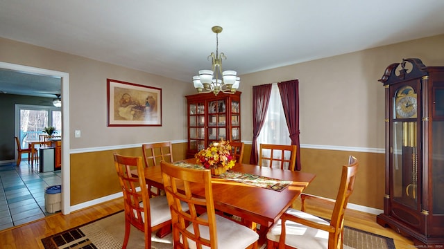 dining space with light hardwood / wood-style floors and ceiling fan with notable chandelier