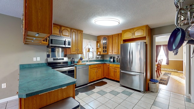 kitchen featuring a textured ceiling, light tile patterned floors, stainless steel appliances, and a baseboard radiator