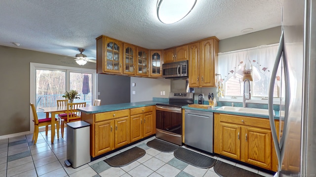 kitchen featuring a textured ceiling, stainless steel appliances, ceiling fan, sink, and light tile patterned floors