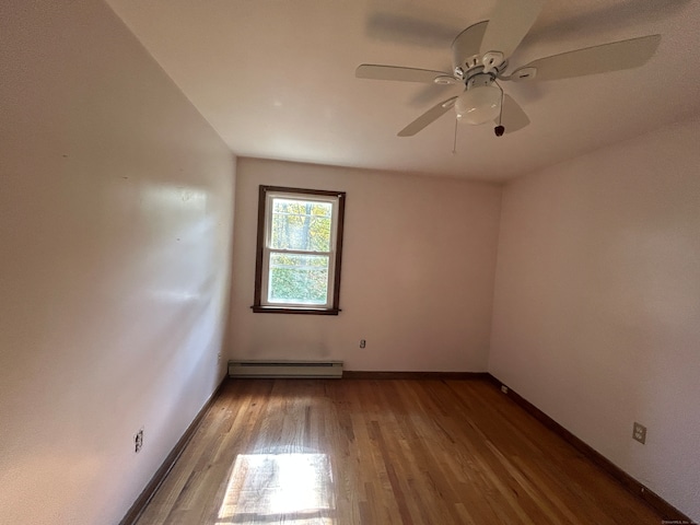 empty room featuring hardwood / wood-style flooring, ceiling fan, and a baseboard heating unit