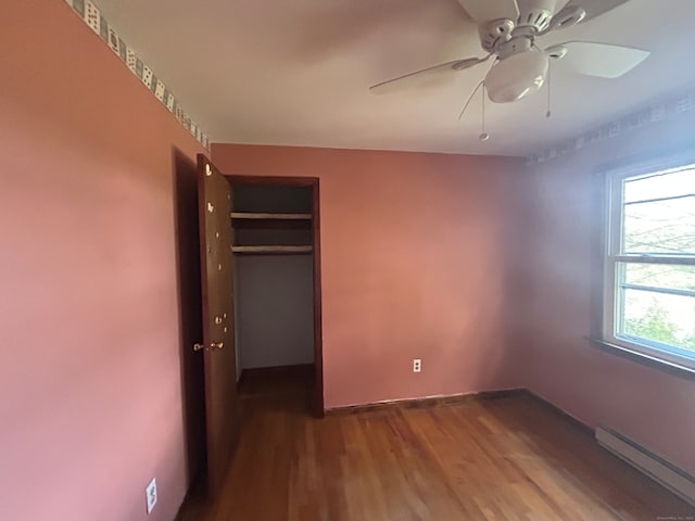 unfurnished bedroom with hardwood / wood-style flooring, ceiling fan, baseboard heating, and a closet