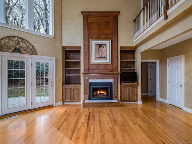 unfurnished living room with light hardwood / wood-style floors, a high ceiling, and a wealth of natural light