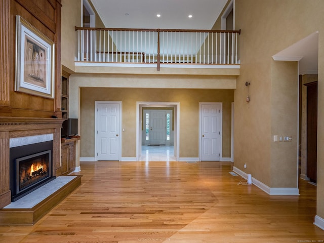 unfurnished living room featuring a towering ceiling and light hardwood / wood-style floors